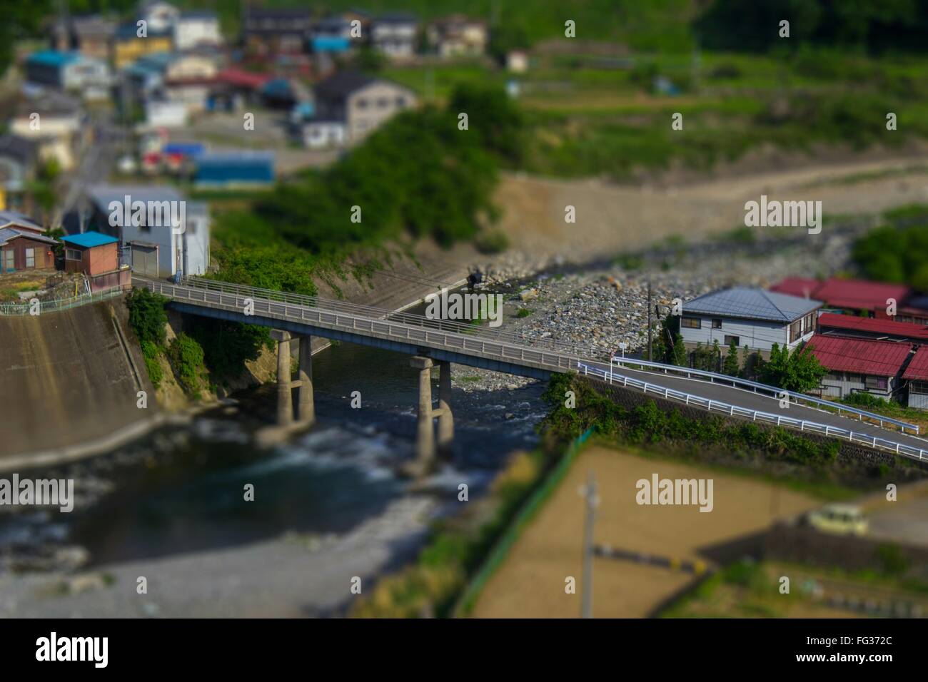 Tilt-Shift Image Of Bridge Over River In City Stock Photo
