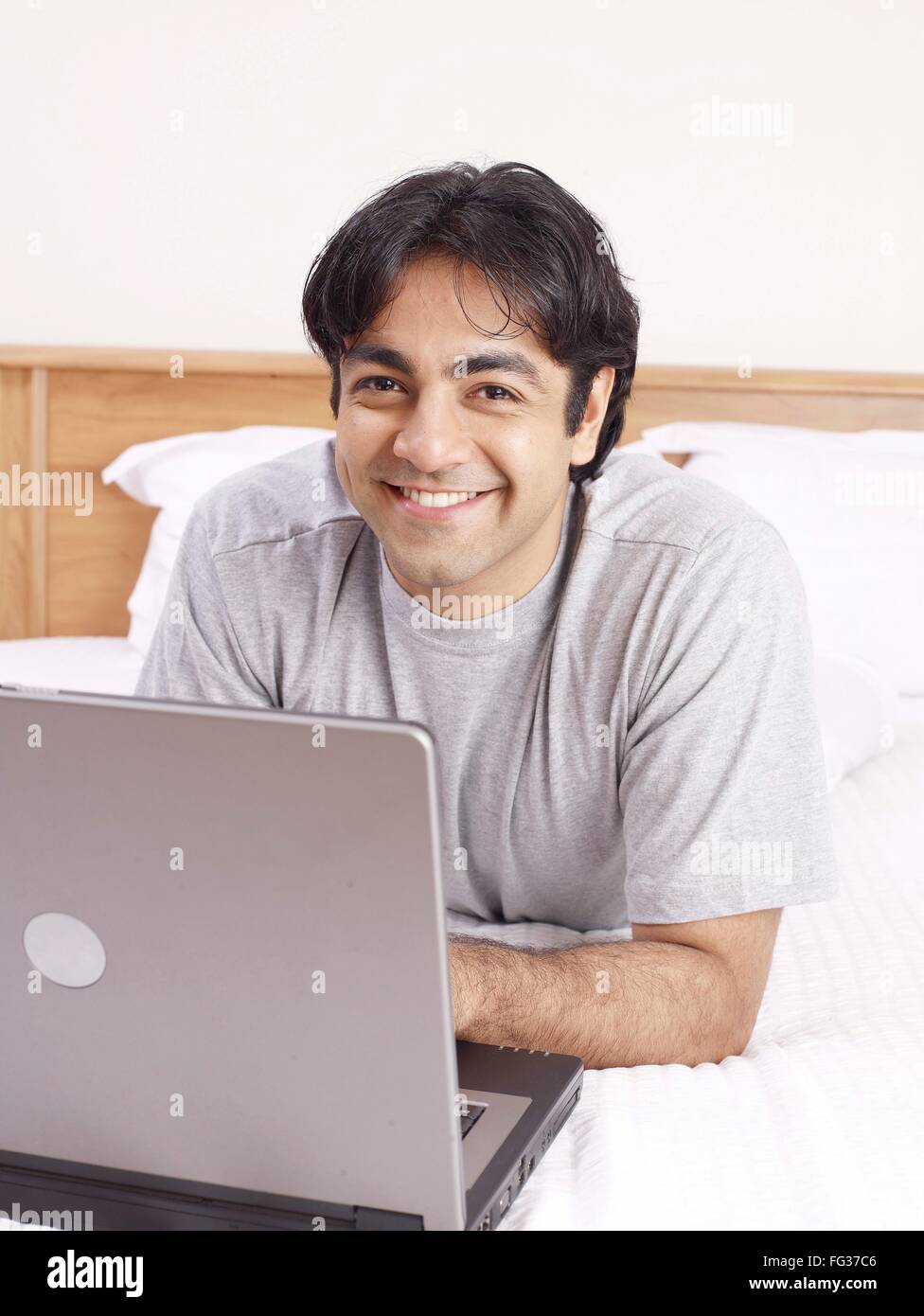 Young man with laptop laying on bed MR#702V Stock Photo