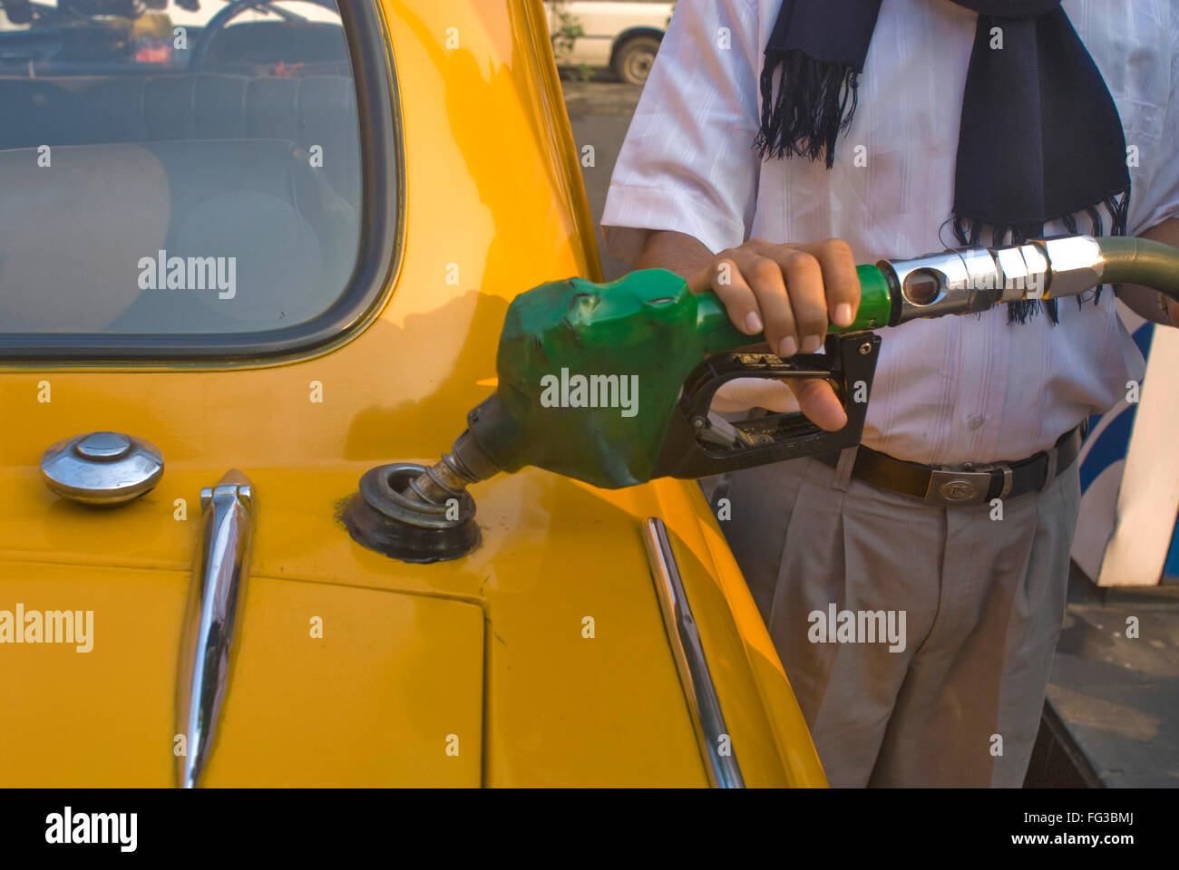 Man filling up petrol in yellow ambassador taxi at petrol pump ; Bhowanipur ; Calcutta ; West Bengal ; India Stock Photo