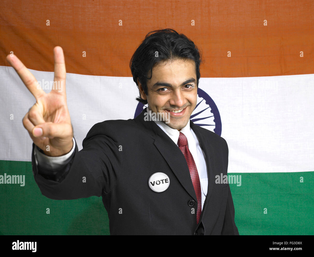Executive showing victory sign standing in front of national flag of India MR#702A Stock Photo