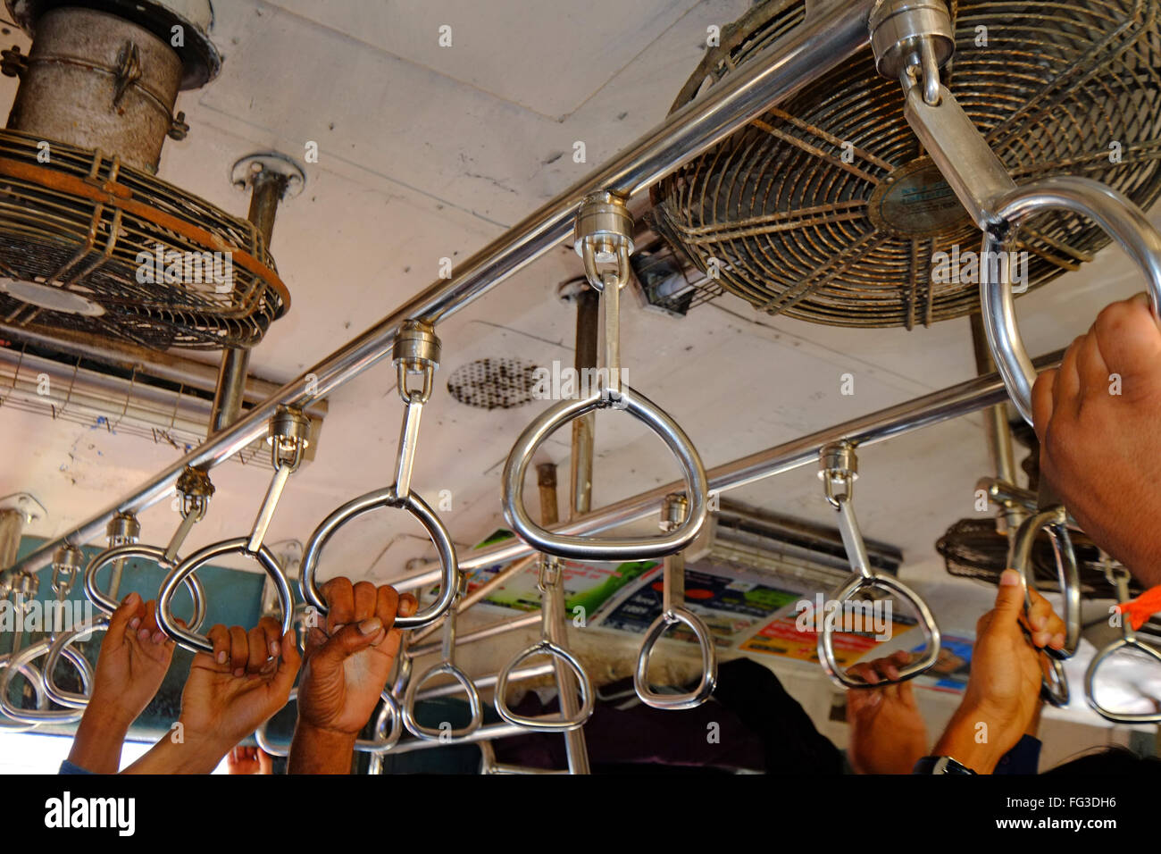 Commuters hang on in a suburban rail carriage, Mumbai India Stock Photo