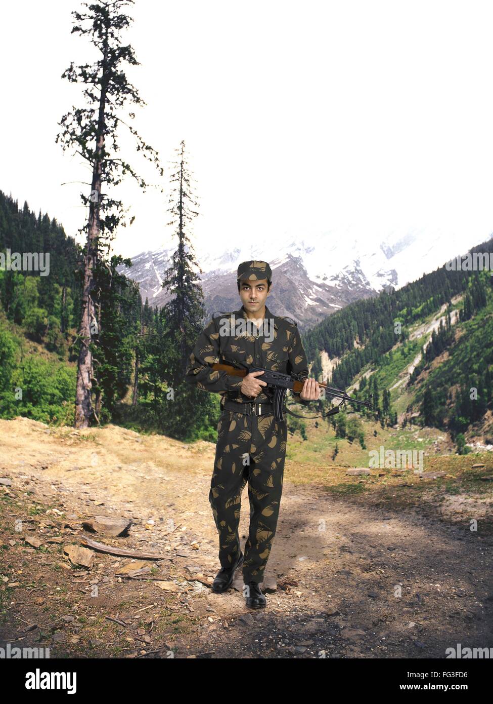 Indian army soldier Ak 47 machine gun in hand mountain in background MR Stock Photo