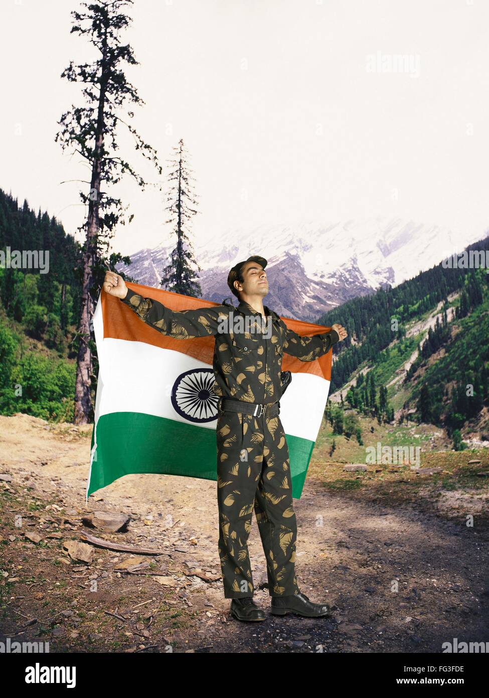 Indian army soldier holding national flag on his backside mountain in background MR Stock Photo