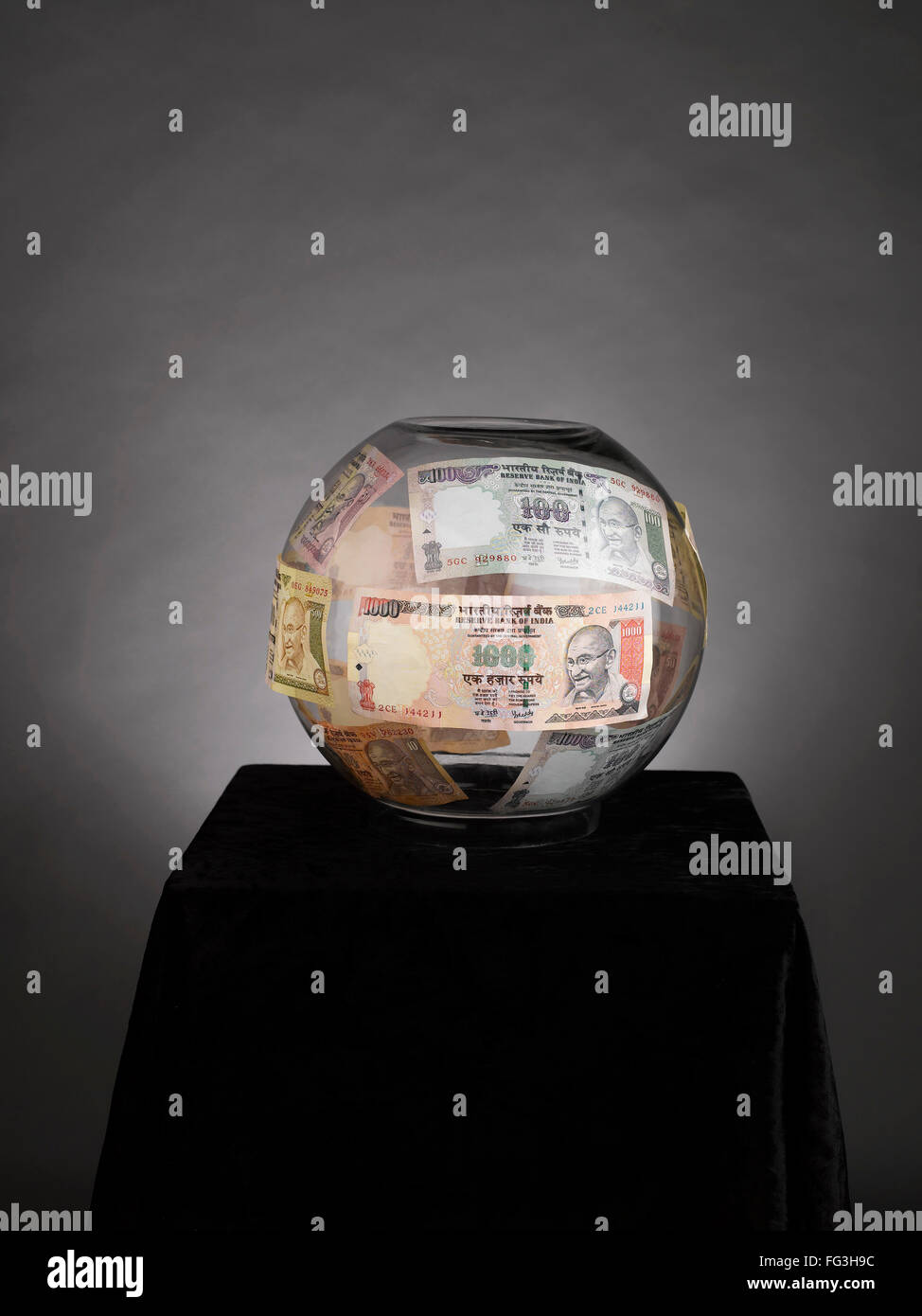 Indian currency notes in glass bowl against gray background Stock Photo