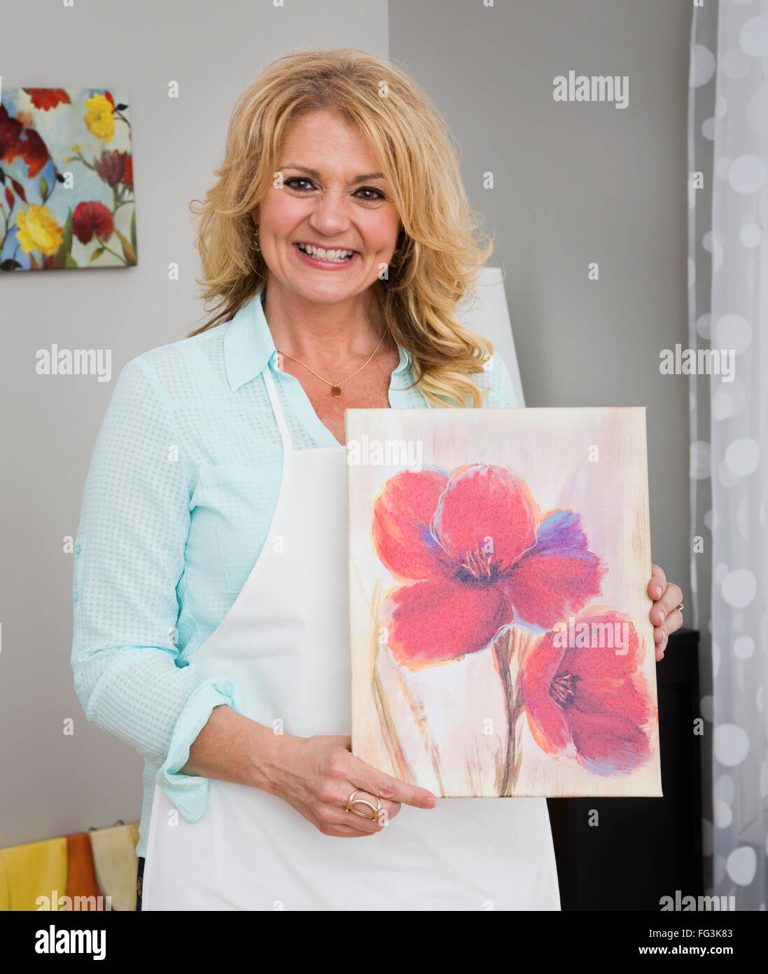 Portrait of mature woman holding painting Stock Photo