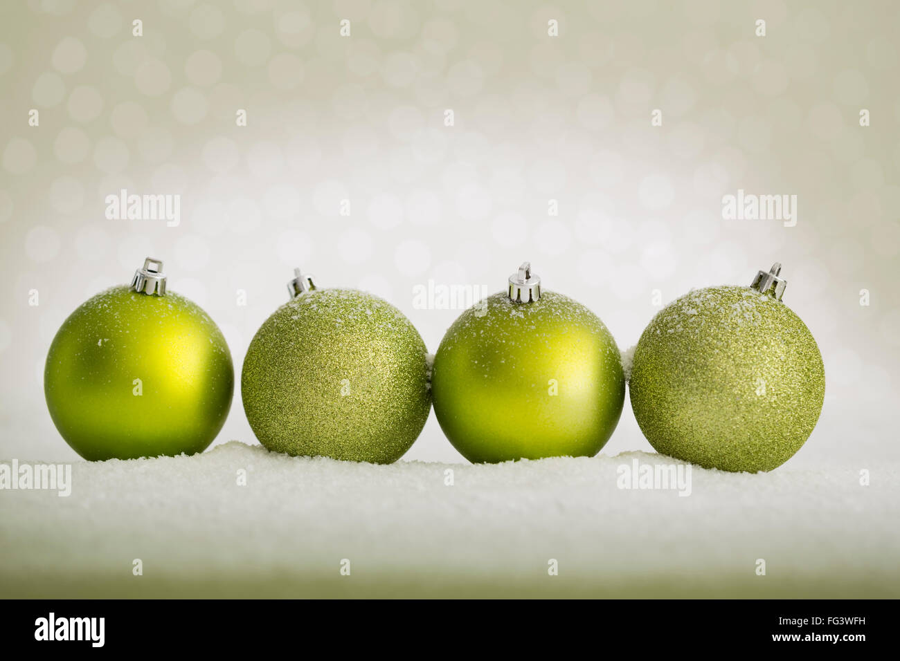 Green baubles in a row on fake snow Stock Photo