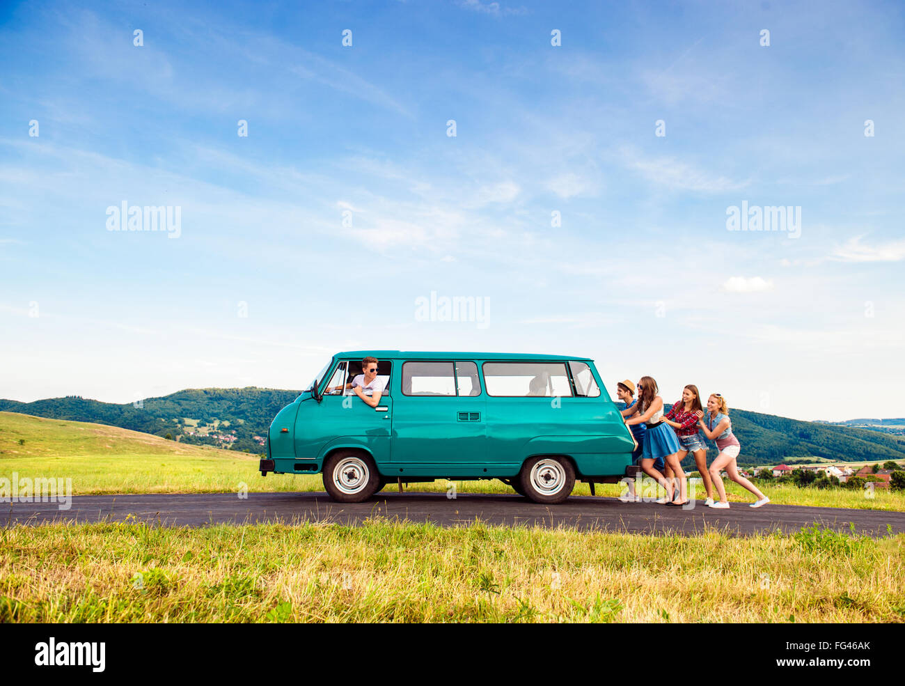 Jumping frieds with campervan, green nature and blue sky Stock Photo