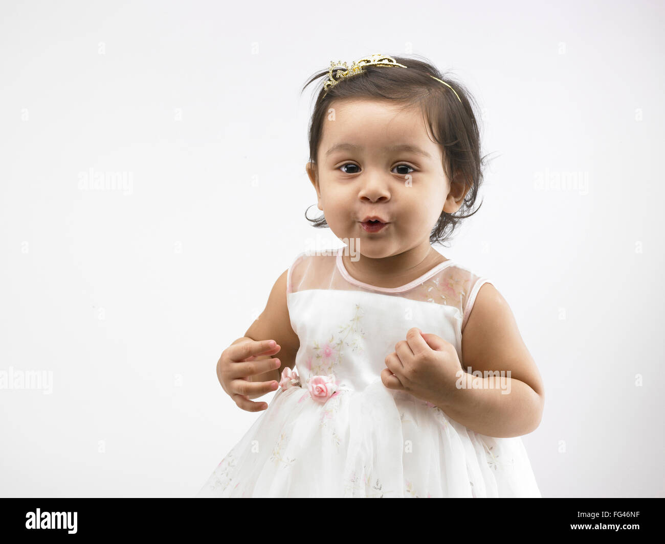Joyful Indian baby girl wearing white dress making funny face MR702O
