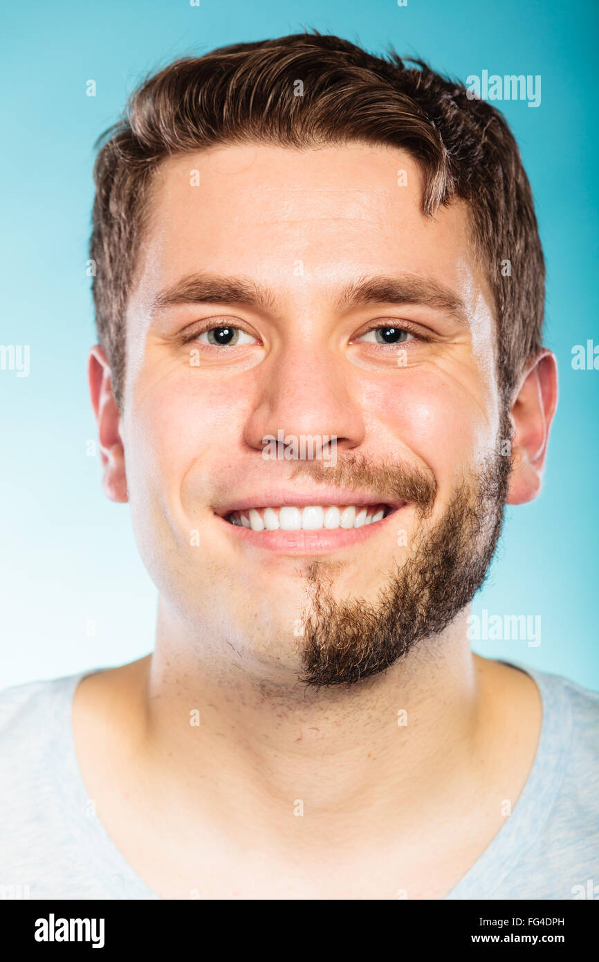 Portrait of happy man with half shaved face beard hair. Smiling handsome guy on blue. Skin care and hygiene. Stock Photo