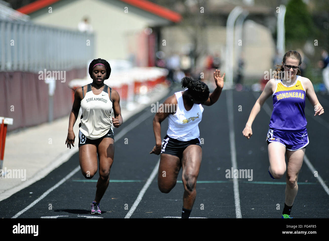 Three high school athletes strain at the finish line in a closely contested 100-meter dash at a high school track meet. USA. Stock Photo