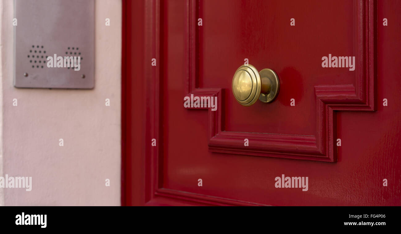 Shiny brass metal doorknob on red wooden entrance door Stock Photo
