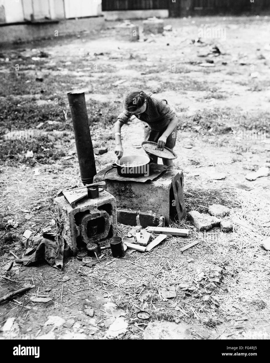 CONCENTRATION CAMP, 1945. /nA Ukrainian girl preparing a meal for her family on a makeshift stove in a concentration camp at Salzburg, Austria. Photograph, May 1945. Stock Photo