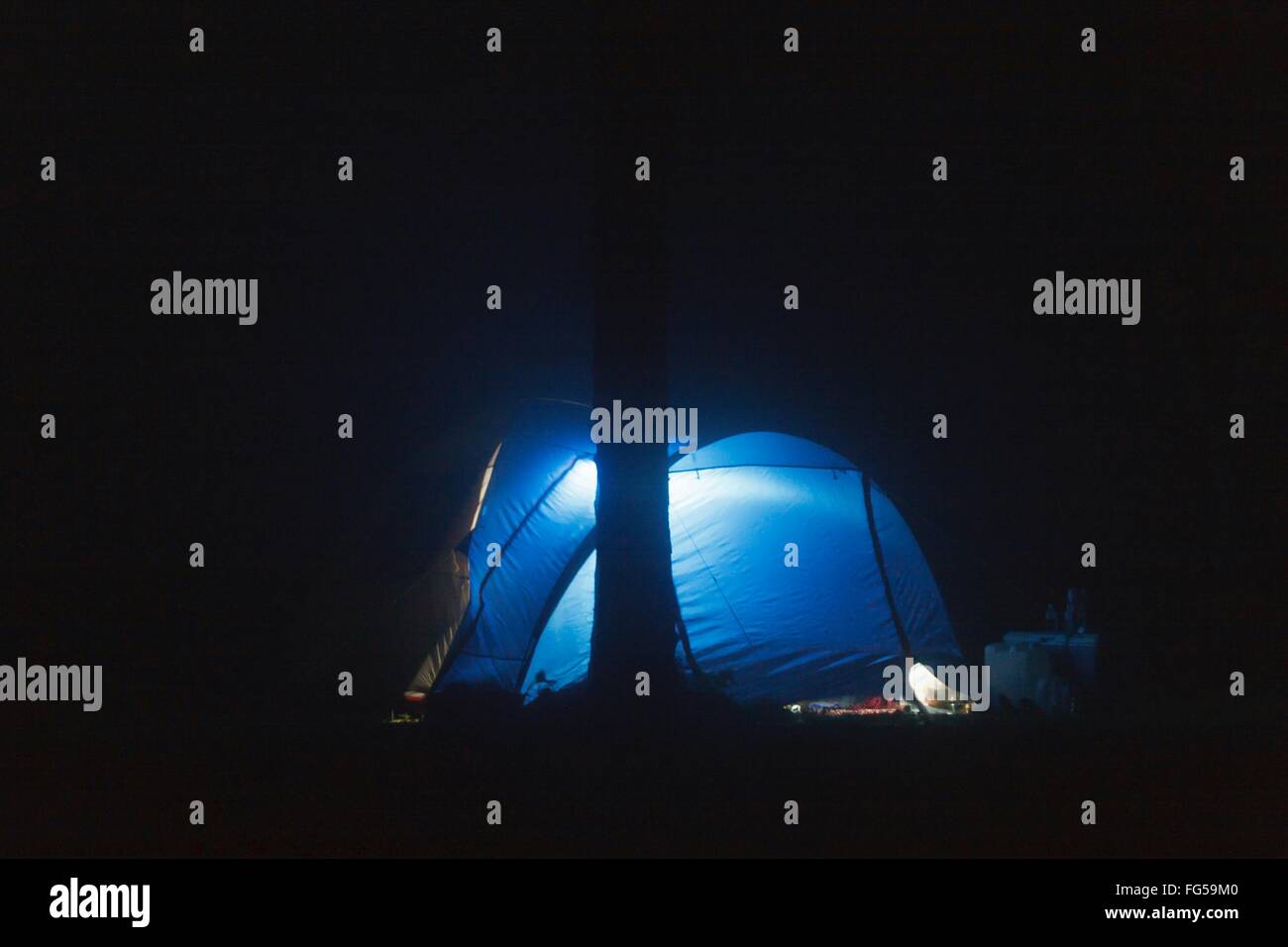 Blue Illuminated Dome Tent On Field At Night Stock Photo