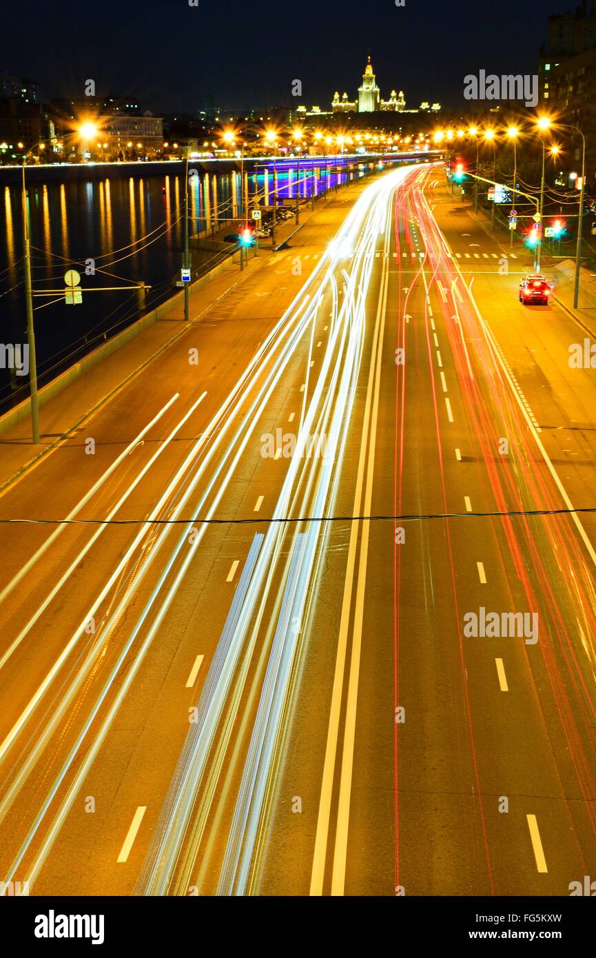 High Angle View Of Light Trails On Illuminated Street By River At Night Stock Photo