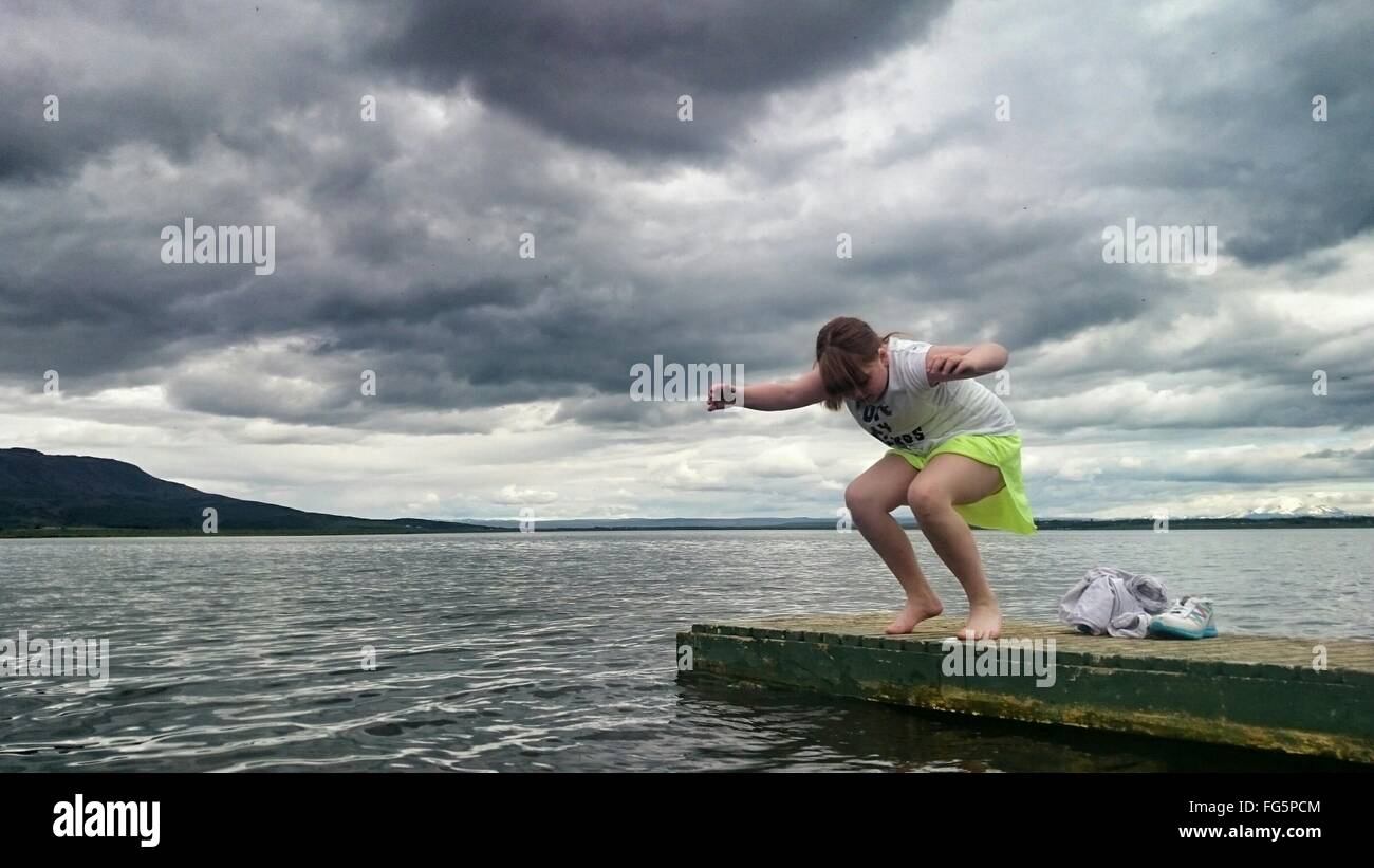 Teenage Girl Jumping In Sea Against Cloudy Sky Stock Photo - Alamy