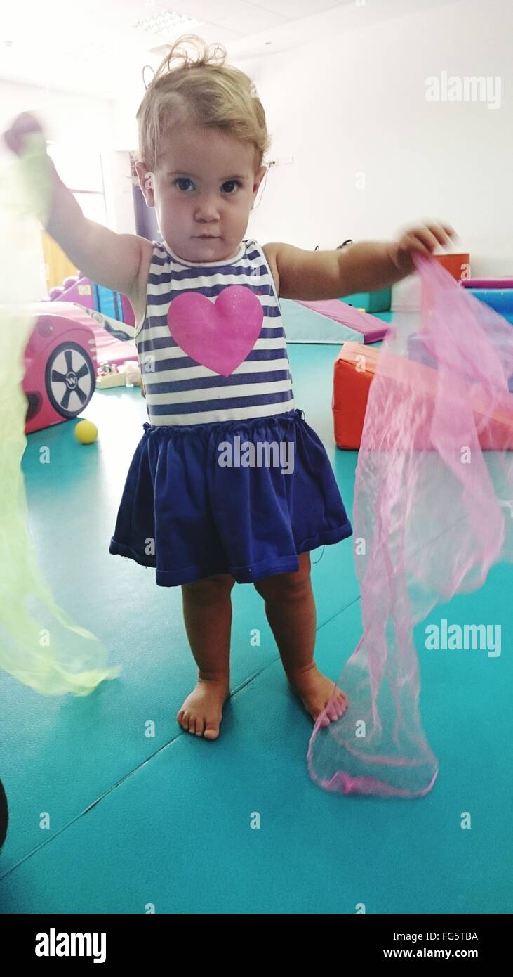 Portrait Of Girl Holding Fabric While Standing At Playroom Stock Photo