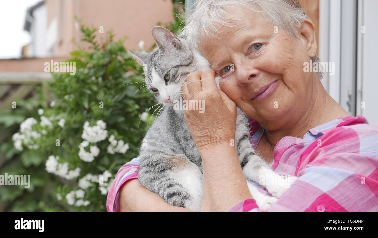 Portrait Of Senior Woman Cuddling Tabby Cat By House Stock Photo