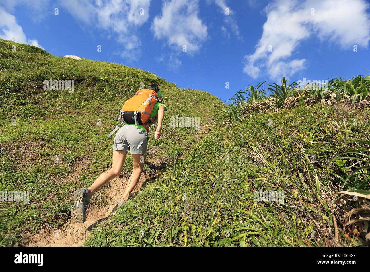 young woman backpacker climbing to mountain peak Stock Photo