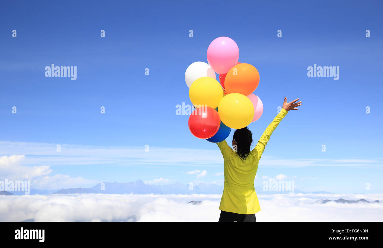 young cheering woman with colorful balloons on mountain peak Stock ...