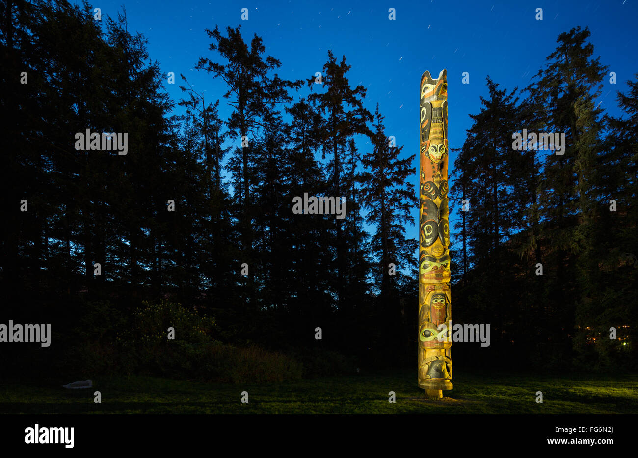 A large Totem Pole lit up at night in Sitka National Historic Park ...