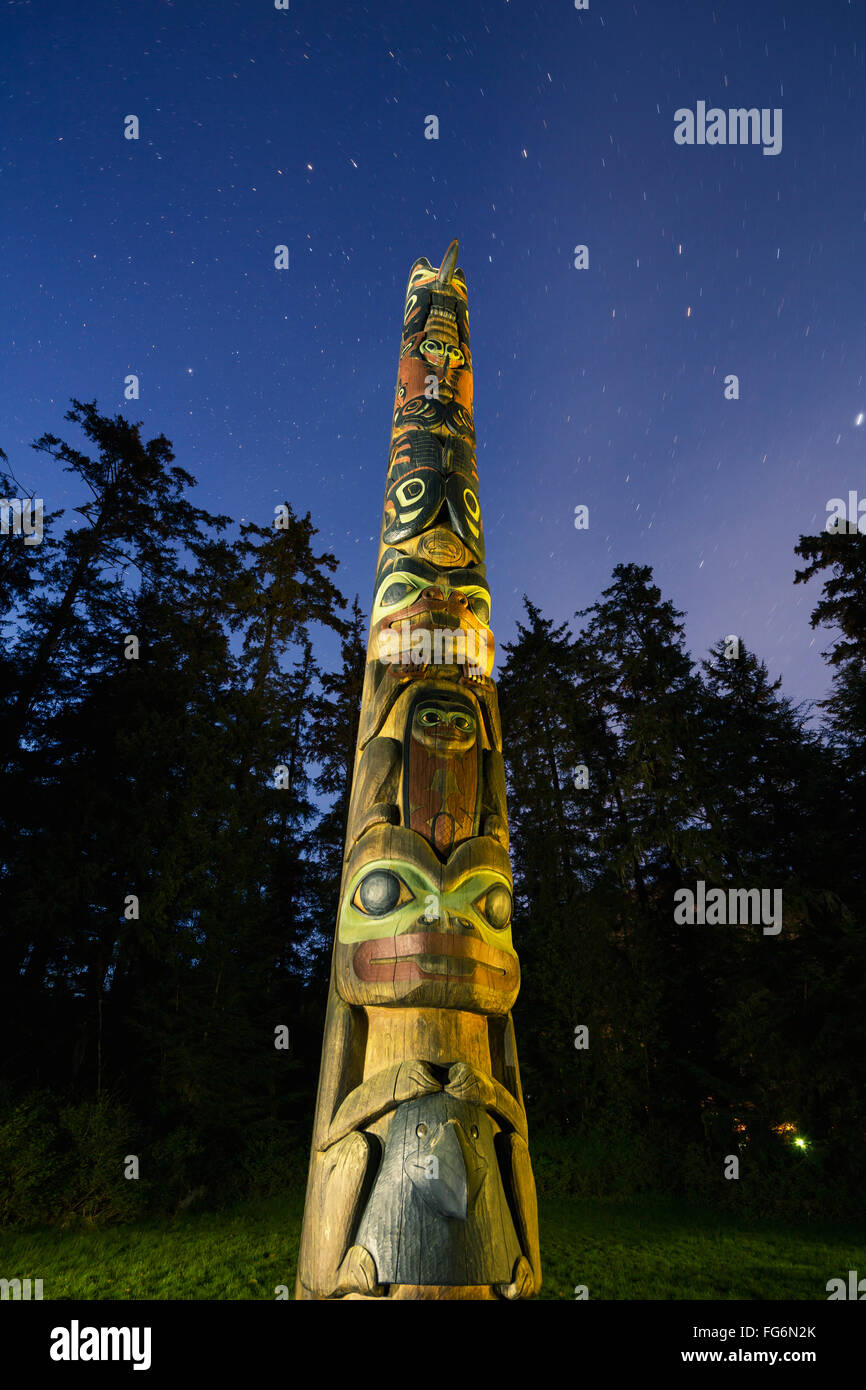 A large Totem Pole lit up at night in Sitka National Historic Park with ...