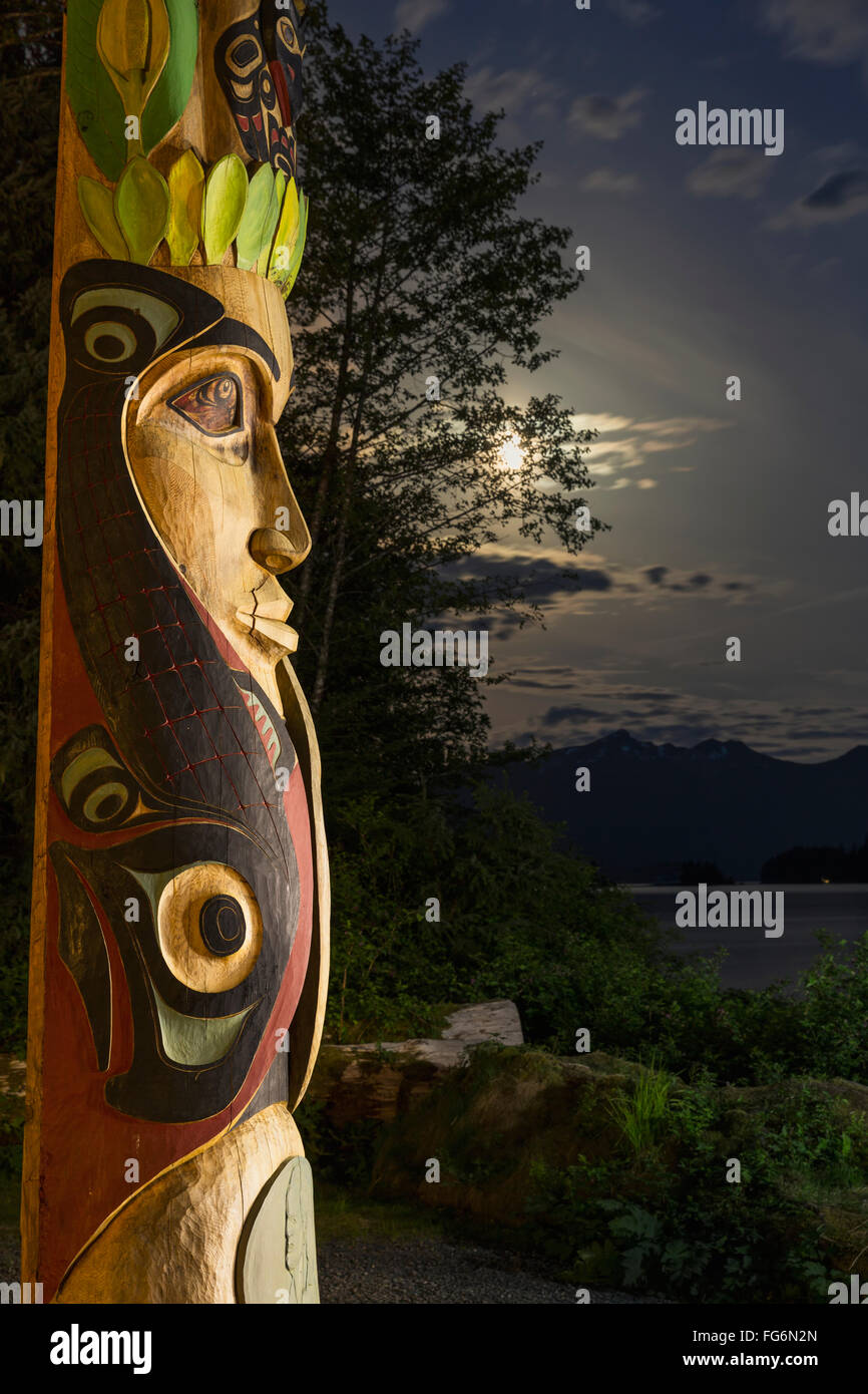 A large totem pole lit up at night in Sitka National Historic Park with ...
