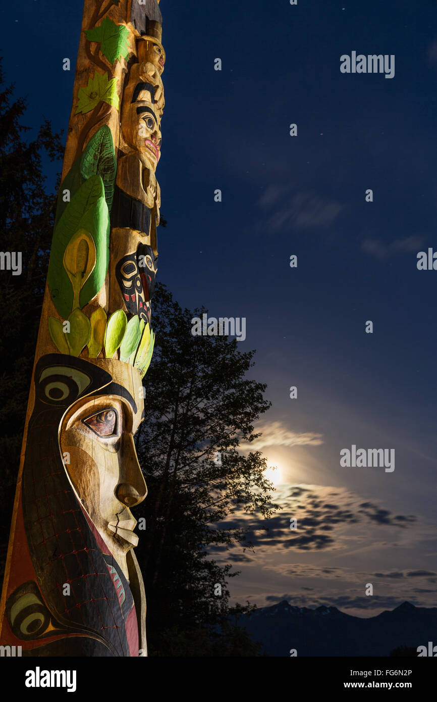 A large totem pole lit up at night in Sitka National Historic Park with ...