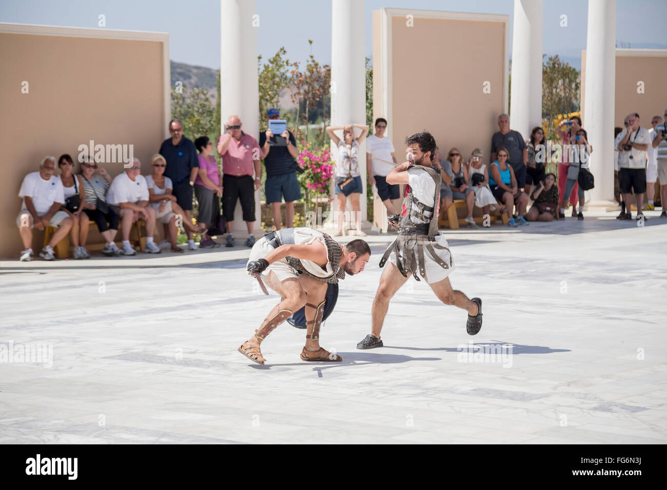 A pair of actors dressed as gladiators fight in a duel in front of a crowd of tourists at a Greek history attraction in Turkey Stock Photo