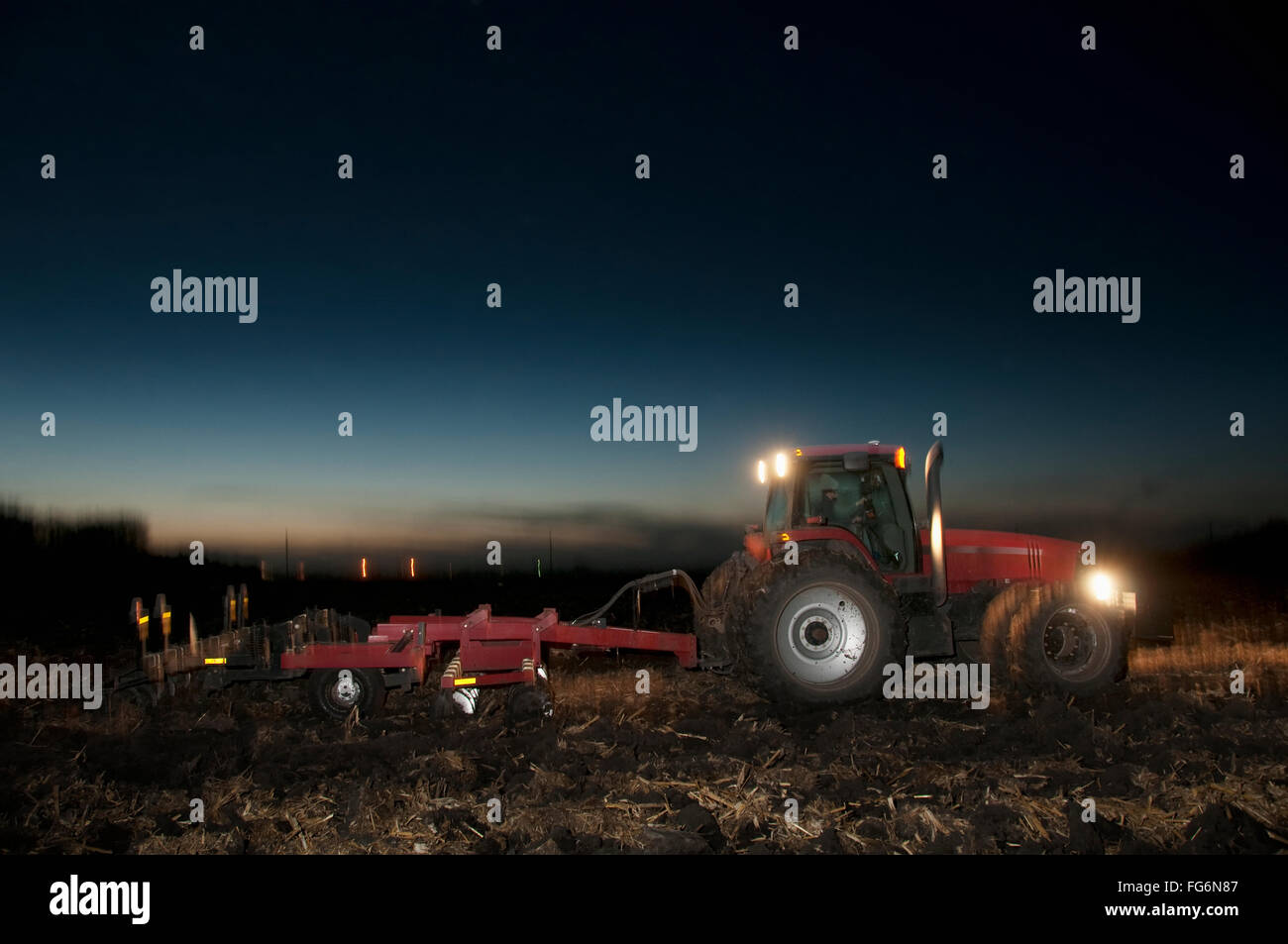 Agriculture - A Tractor Pulling A Disk Ripper At Dusk Tills A Field Of ...