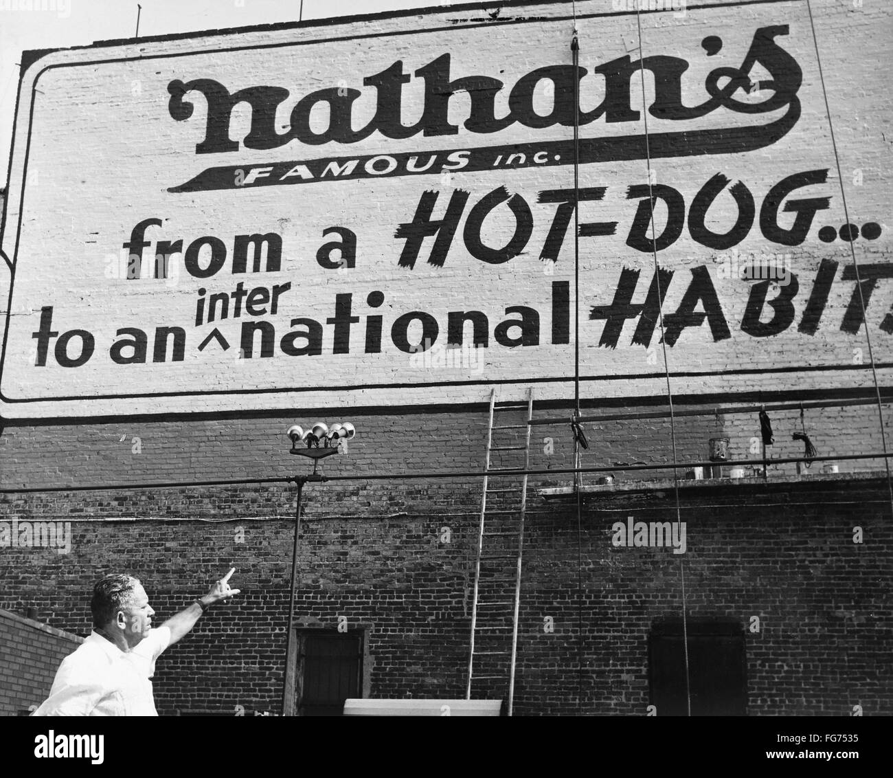 NYC NATHAN'S, 1959. /nFounder Nathan Handwerker pointing at a sign for