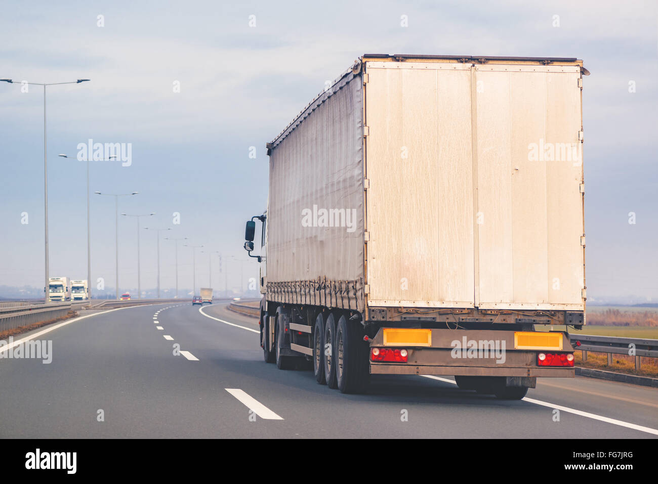 Commercial trailer truck in motion on Eastern Europe freeway on cloudy autumn afternoon, cargo transportation. Stock Photo