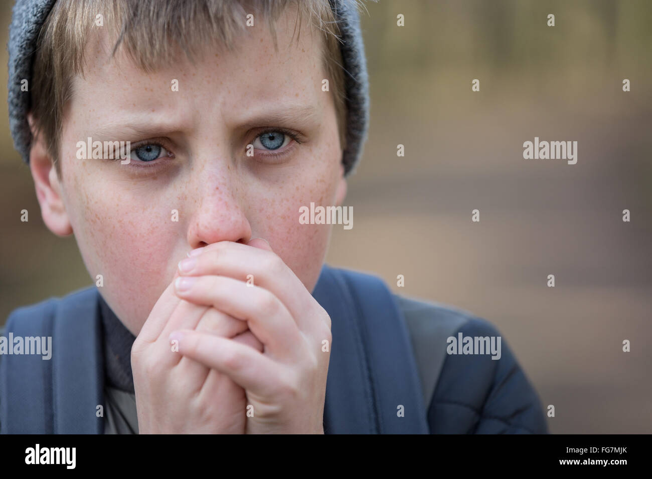 A cold boy in the woods trying to keep warm Stock Photo