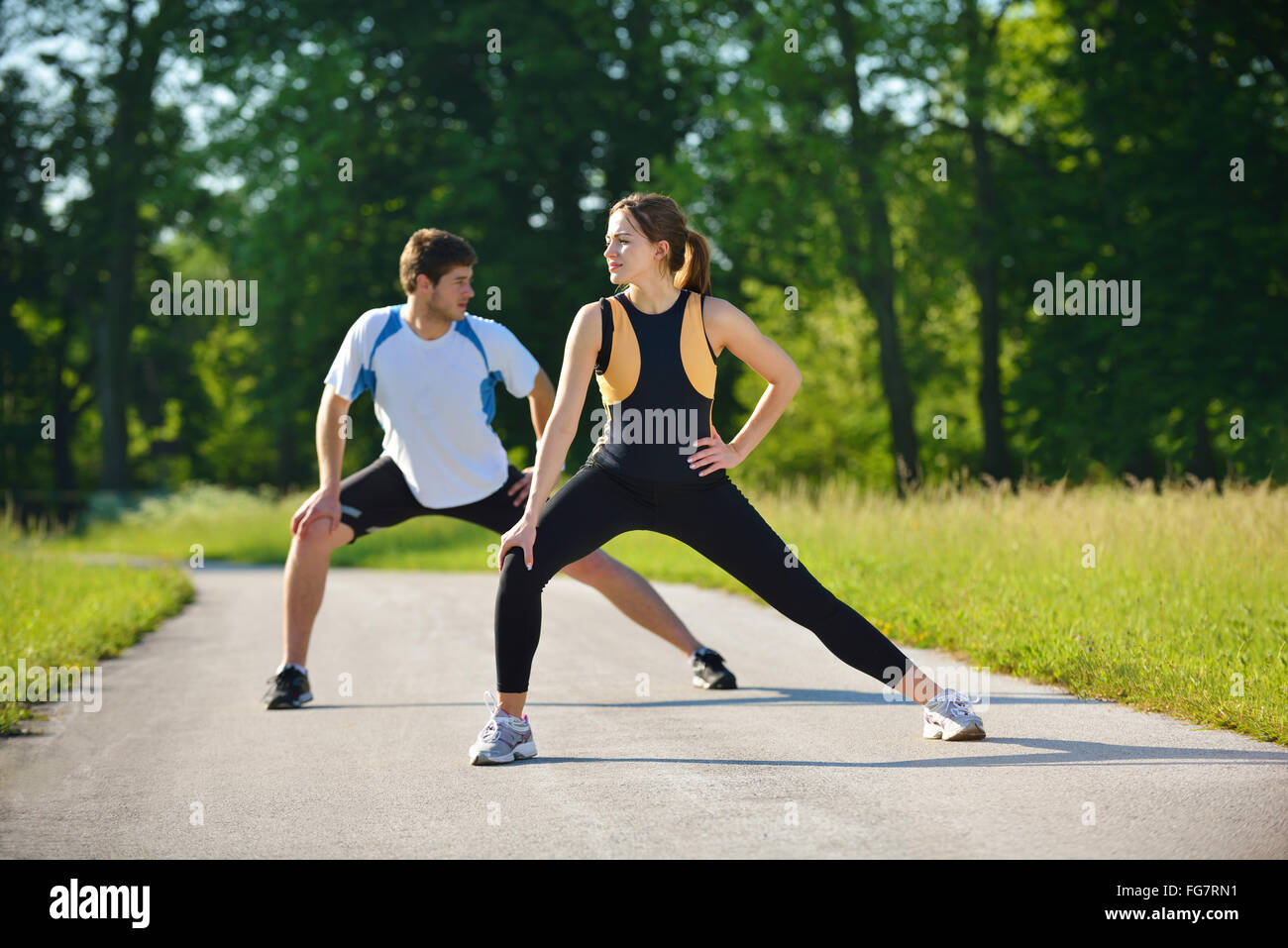 Couple doing stretching exercise after jogging Stock Photo - Alamy