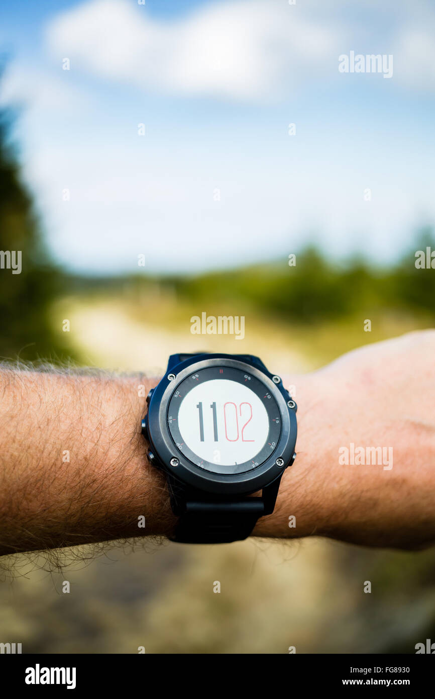 Runner on mountain trail looking at stopwatch smartwatch, activity