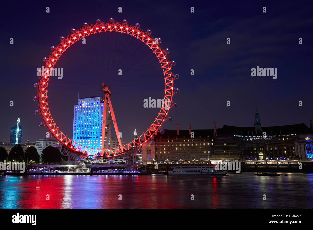 London eye, ferris wheel, illuminated in red in the night, reflection