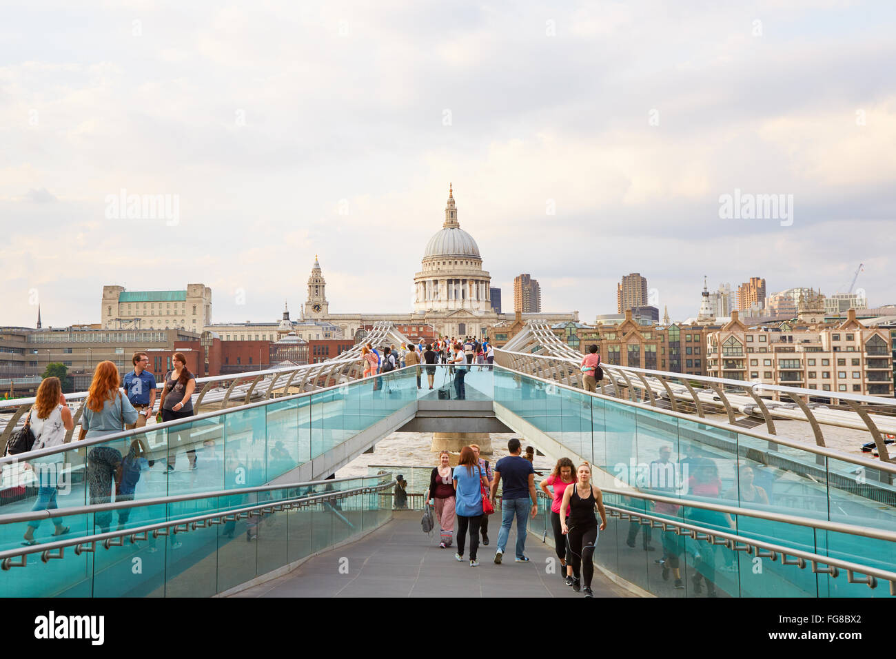 Millennium bridge with people walking and St Paul cathedral in a summer evening in London Stock Photo