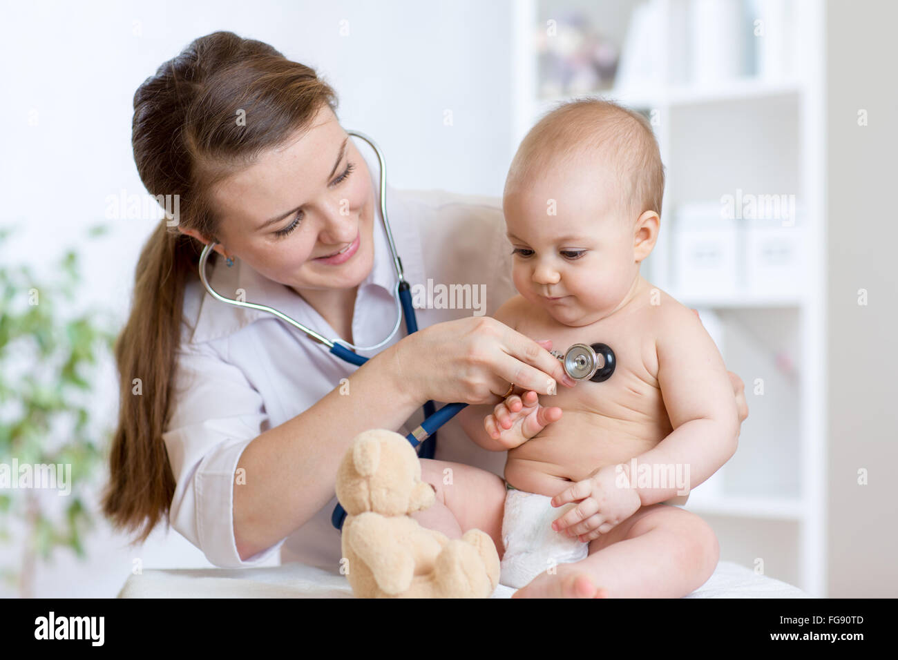Cute woman pediatrician examining of baby kid with stethoscope Stock Photo