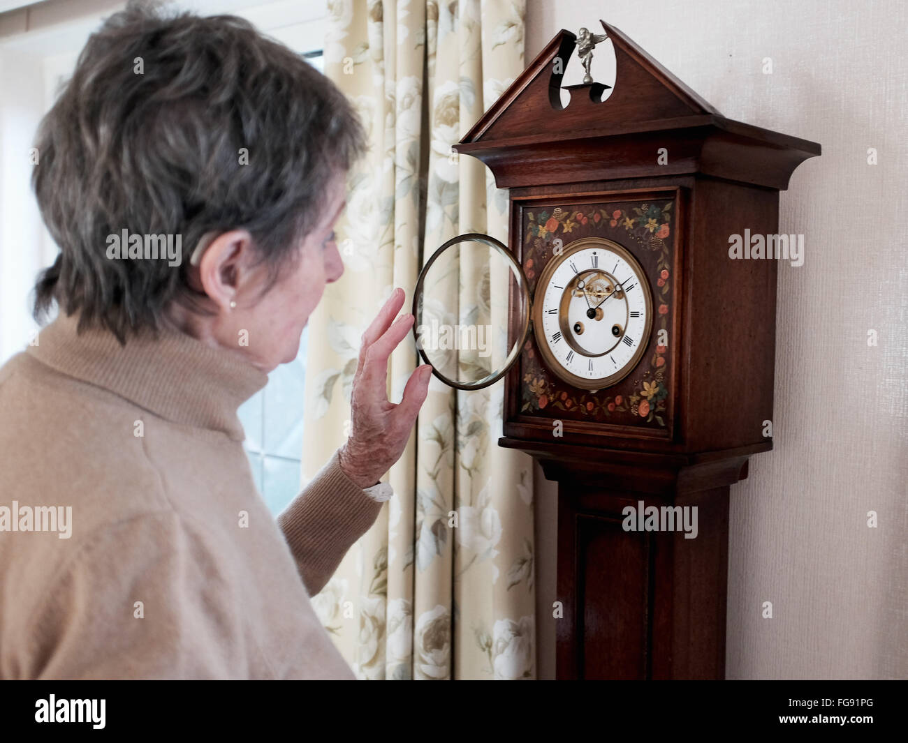 Elderly lady winding up her antique Grandaughter Clock in her dining