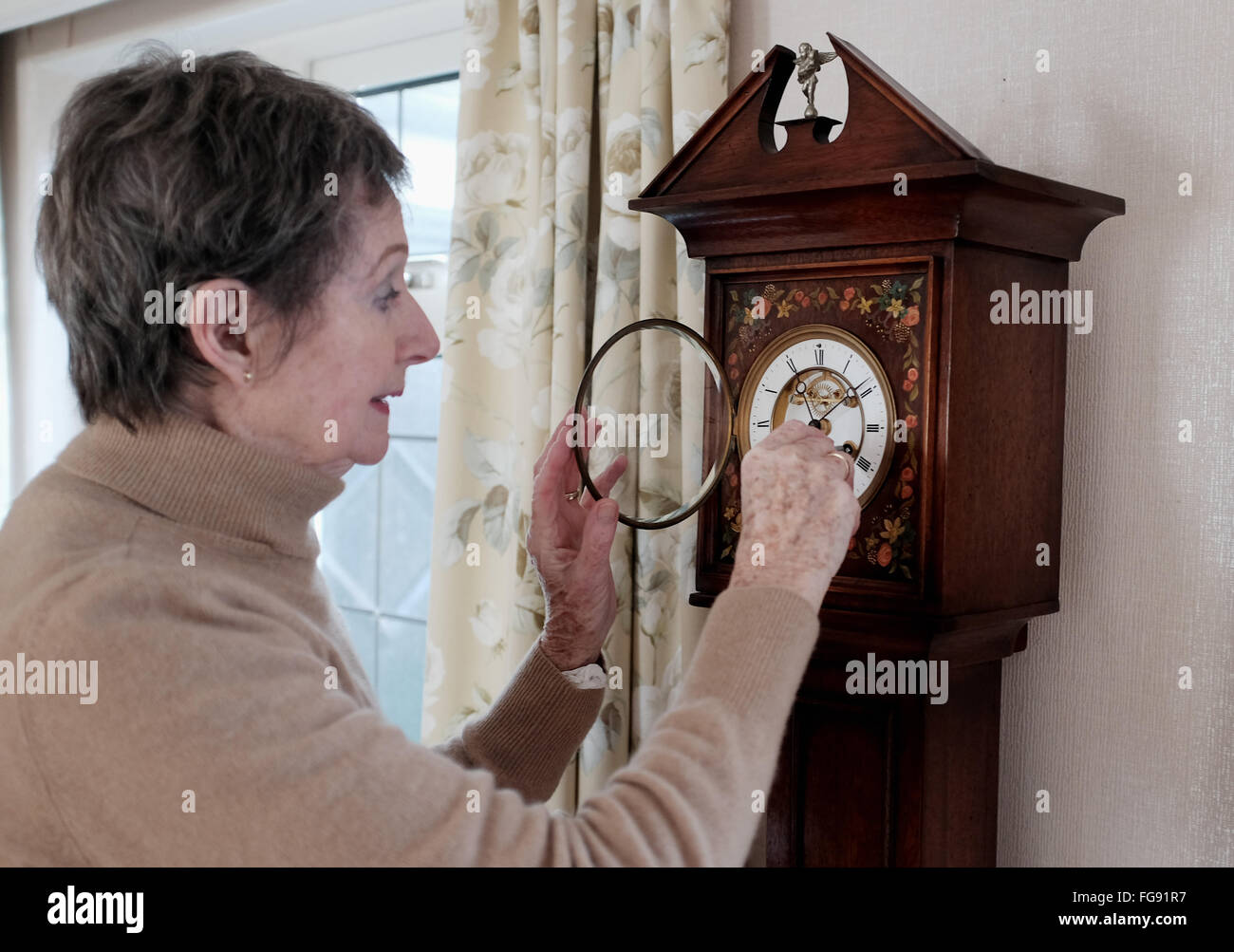 Elderly lady winding up her antique Grandaughter Clock in her dining