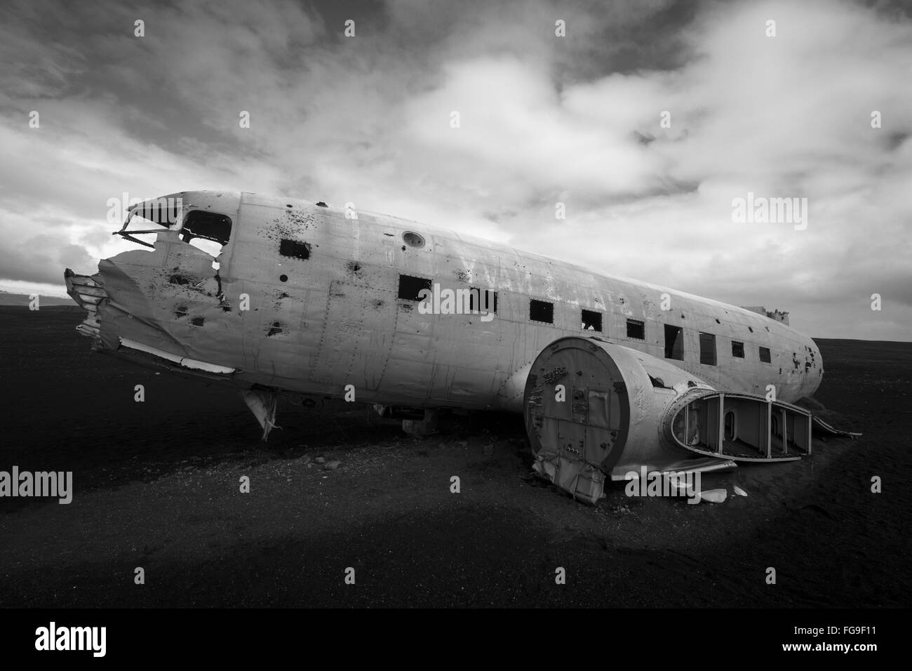 Black and white horizontal side view of a plane wreck on black sands and background of blue sky in south of Iceland Stock Photo