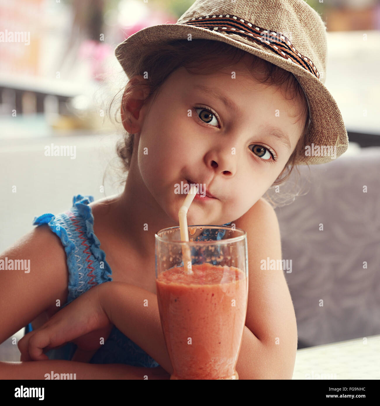 Fun cute kid girl drinking healthy smoothie juice in street restaurant. Closeup toned portrait Stock Photo