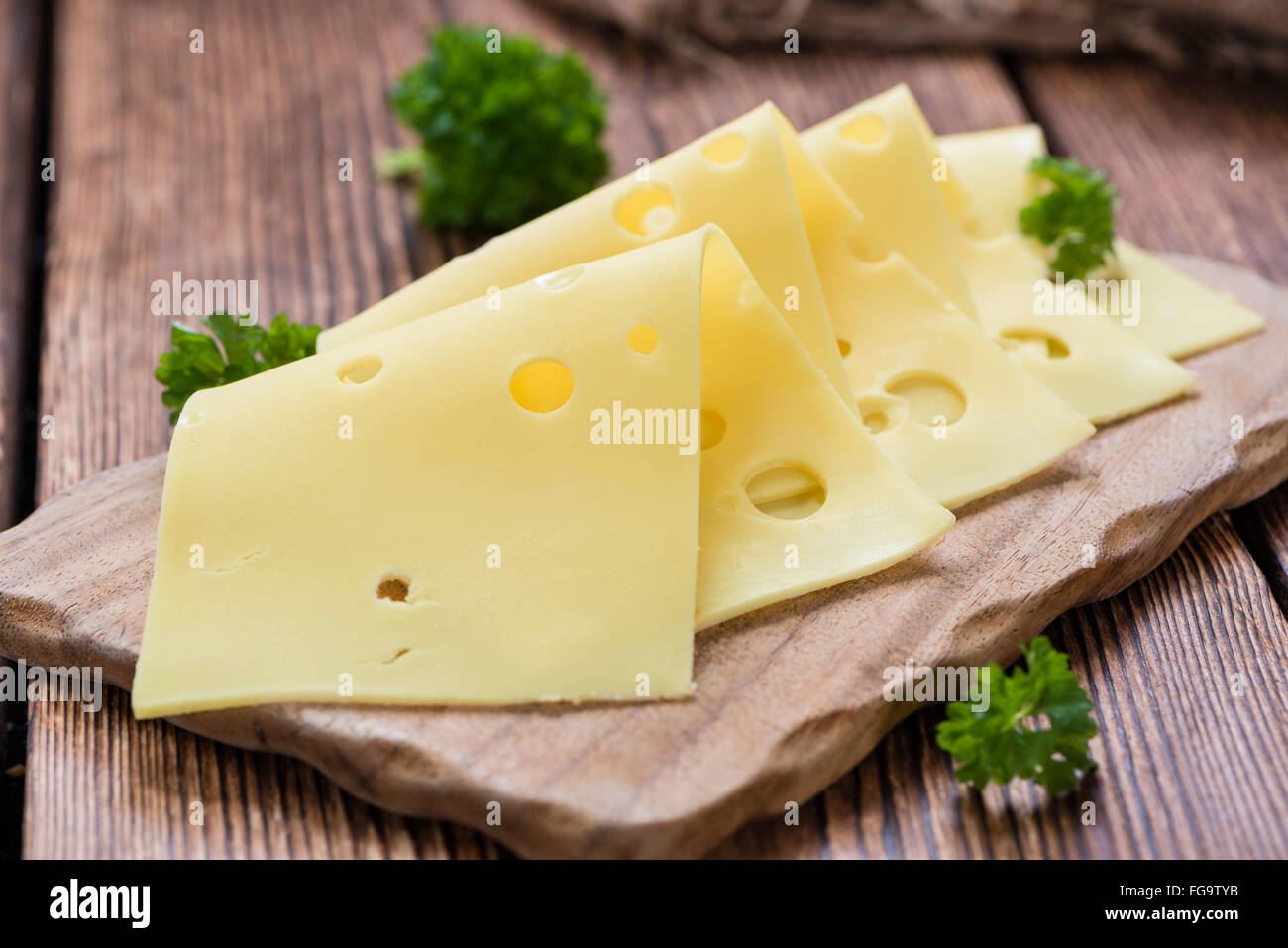 Sliced Cheese (close-up shot) on vintage wooden background Stock Photo