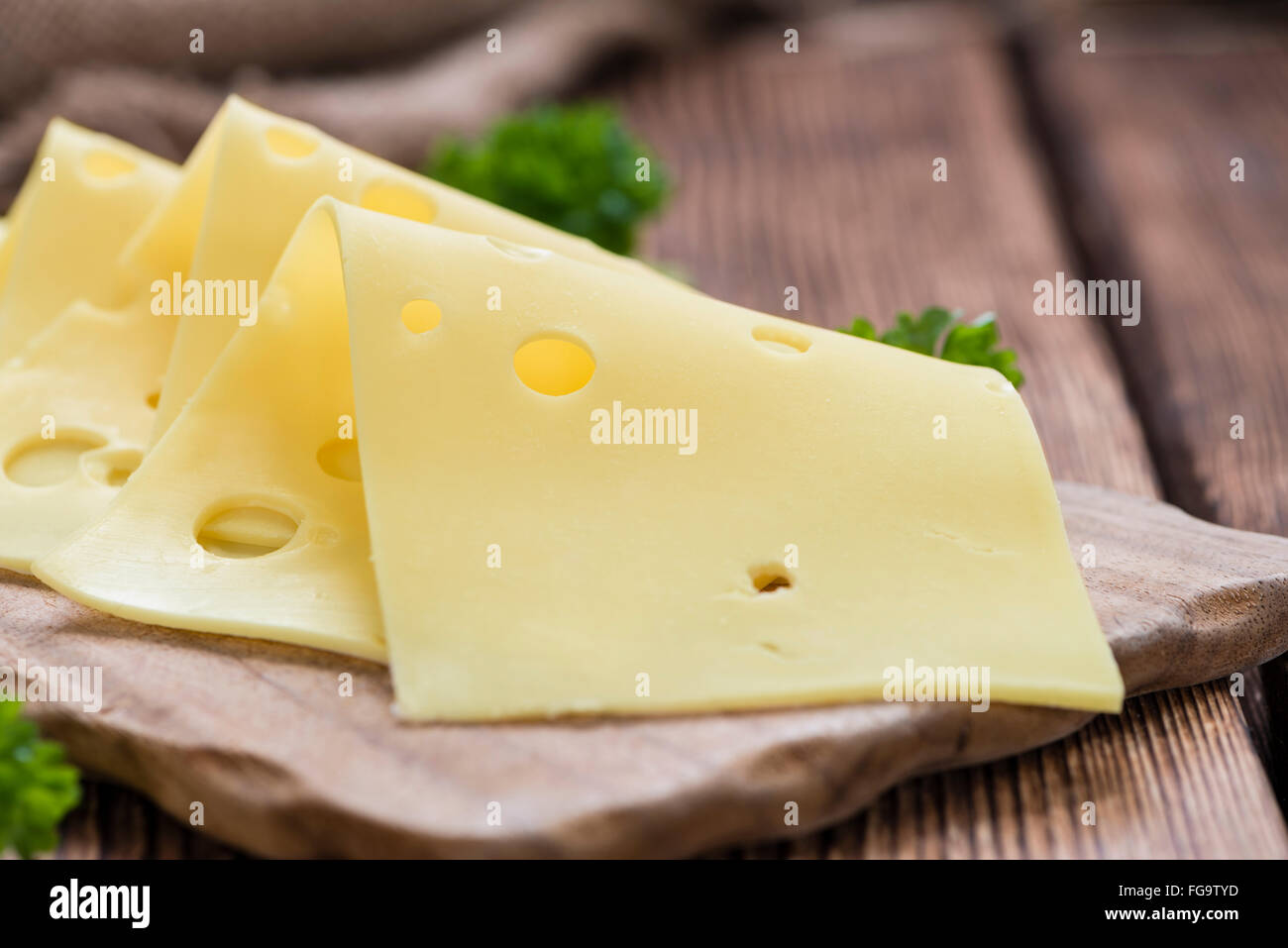 Sliced Cheese (detailed close-up shot) on rustic wooden background Stock Photo