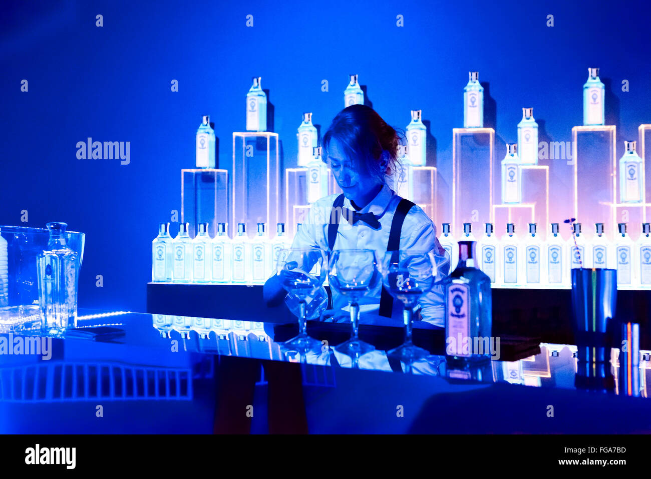 18th February 2016 Madrid, Spain. A female bar tender preparing drinks in the #TheatreRoom. The Bombay Sapphire have designed the MBFW 2016 Madrid kissing room with a spacious blue themed mirror surround hall, #TheatreRoom,  and The Art Room, with large LED screen that reflects the movements of people using Wii type technology at MBFW 2016 Madrid, Spain. © Lawrence JC Baron/Alamy Live News. Stock Photo
