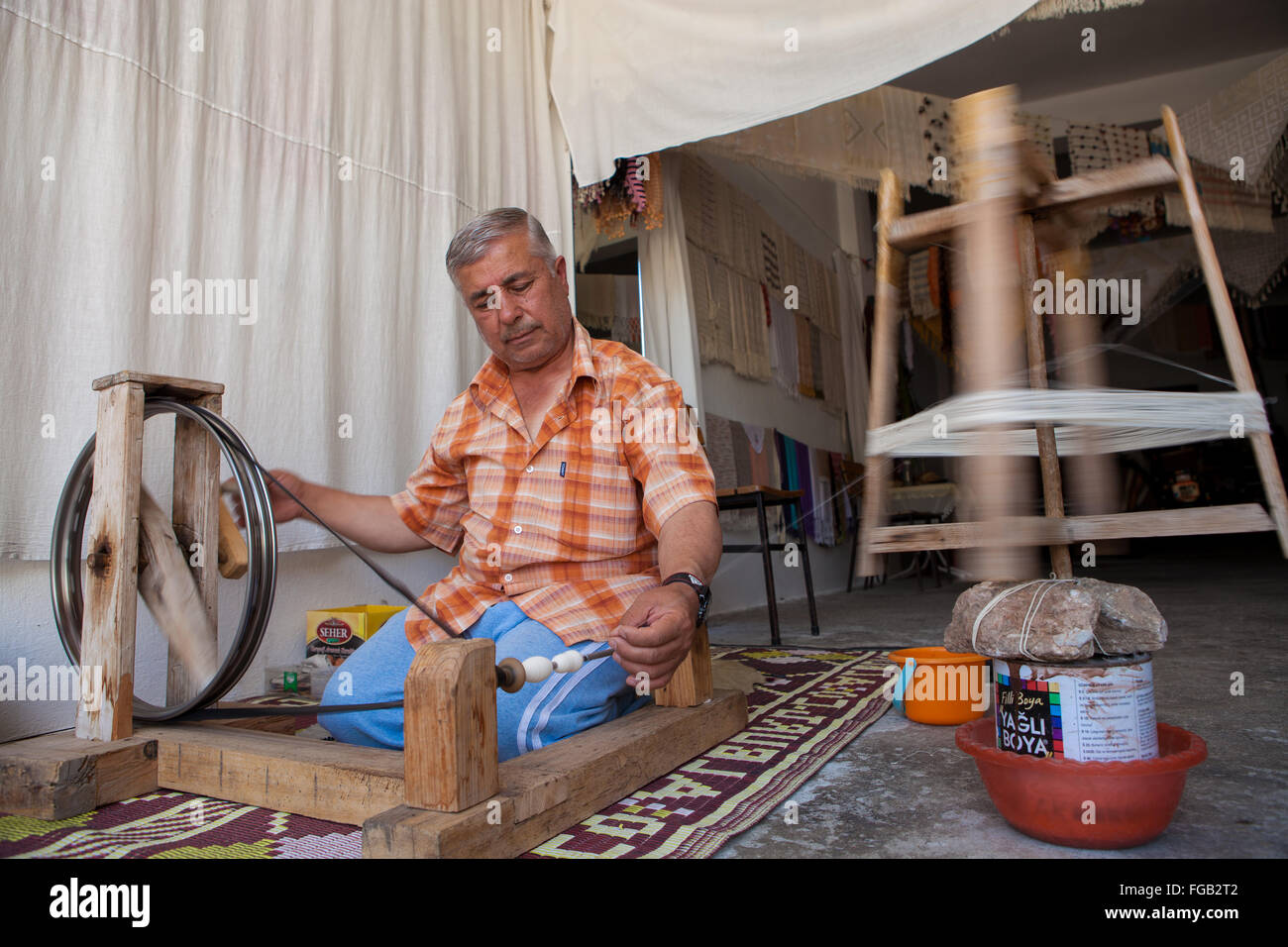 A man sitting on the floor spinning cotton on a loom, Turkey Stock Photo