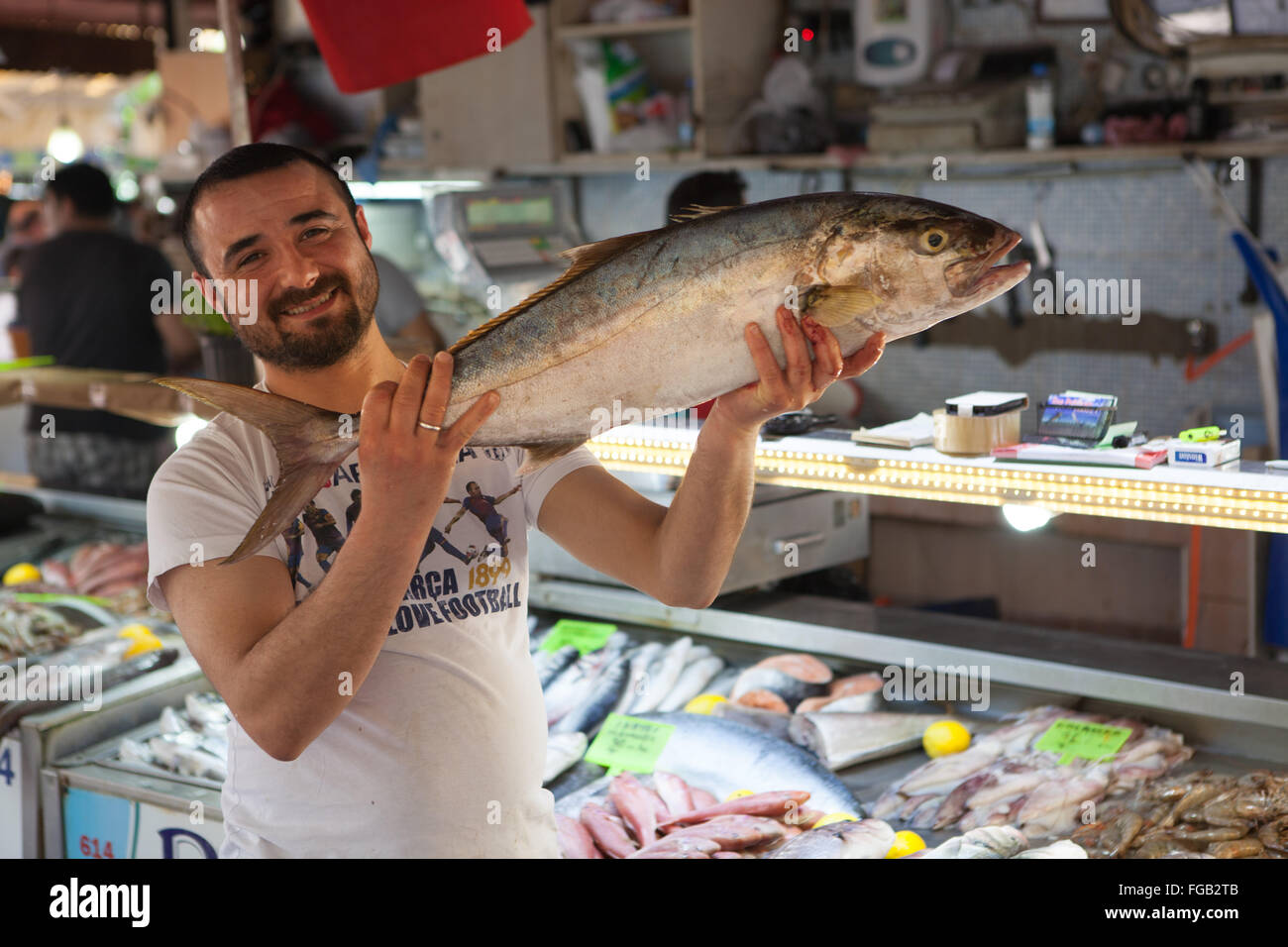 A fishmonger holds up a freshly caught fish in the fish market, Fethiye