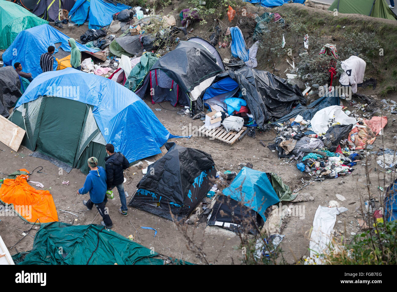 Men walk through makeshift shelters in the crowded Jungle Refugee Camp, Calais, France. Stock Photo