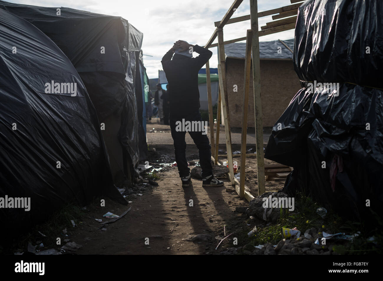 A man stands among makeshift shelters in the Jungle Refugee camp in Calais, France Stock Photo