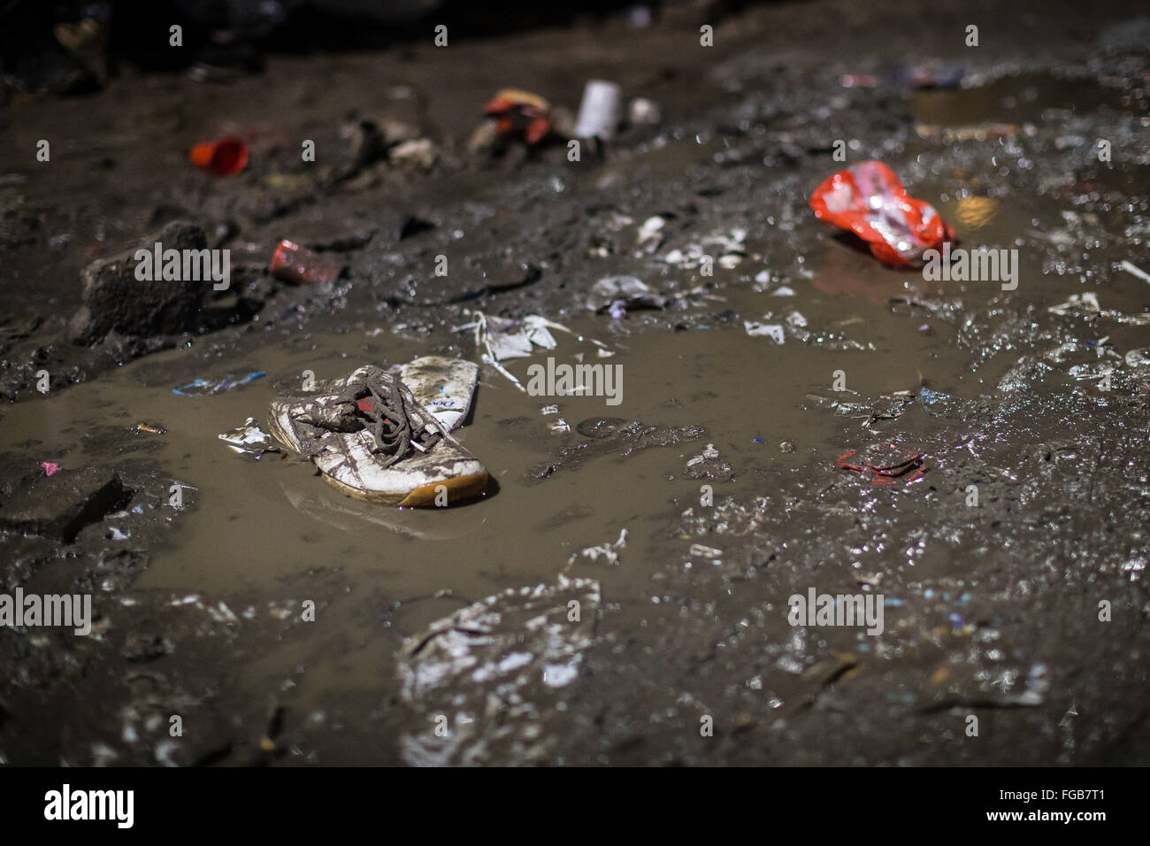 A single trainer sits alongside rubbish in a muddy puddle in the Calais Refugee Camp, also know as the Jungle. Stock Photo
