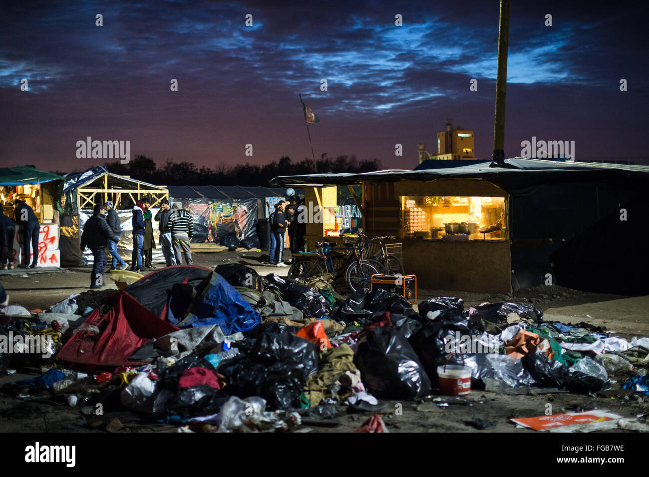 Rubbish builds up in an open area in front of a cafe restaurant and shop in the Jungle refugee camp, Calais, France. Stock Photo